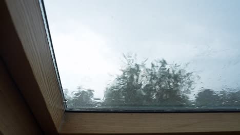 close-up view of raindrops hitting and streaming down a window from the interior perspective