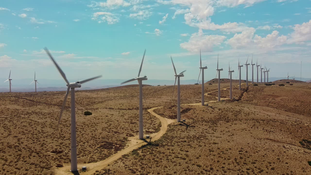 una fila de molinos de viento conectados por un camino en la cima de una colina que produce energía verde a partir de una fuente renovable
