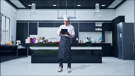 cuerpo lleno de cocinero hombre asiático usando una tableta mientras estaba de pie en la cocina de casa