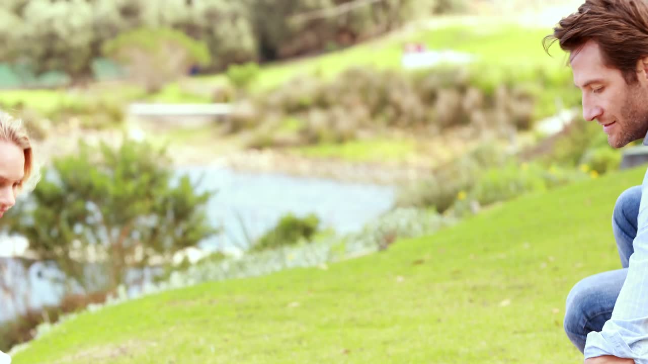 귀여운 커플이 피크닉 담요를 세우고 있다