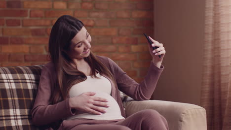 pregnant woman video calling on smartphone