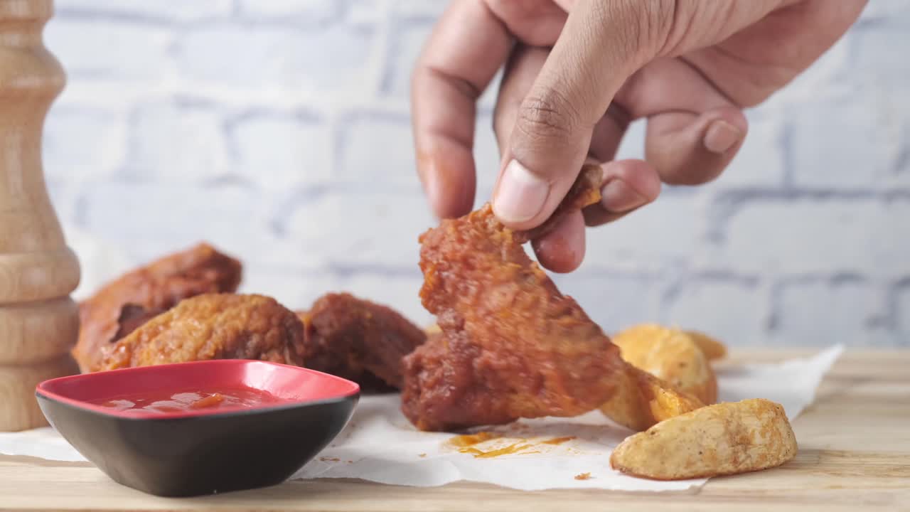 recogiendo a mano alas de pollo frito y cuñas de patata