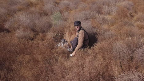 a man in the field training with his falcon that caught a pigeon