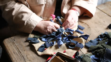 Rag-rug-textile-handcraft-on-a-rustic-wooden-table,-surrounded-by-fabric-scraps