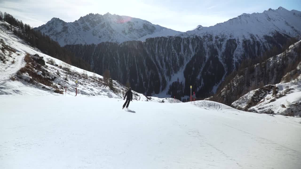 Skier slowly making turns while getting passed by a snowboarder on a clean white slope in the Austrian alps