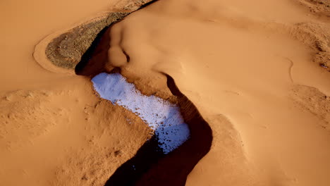 looking straight down, a drone captures the strange and stunning terrain of pink sand dunes.