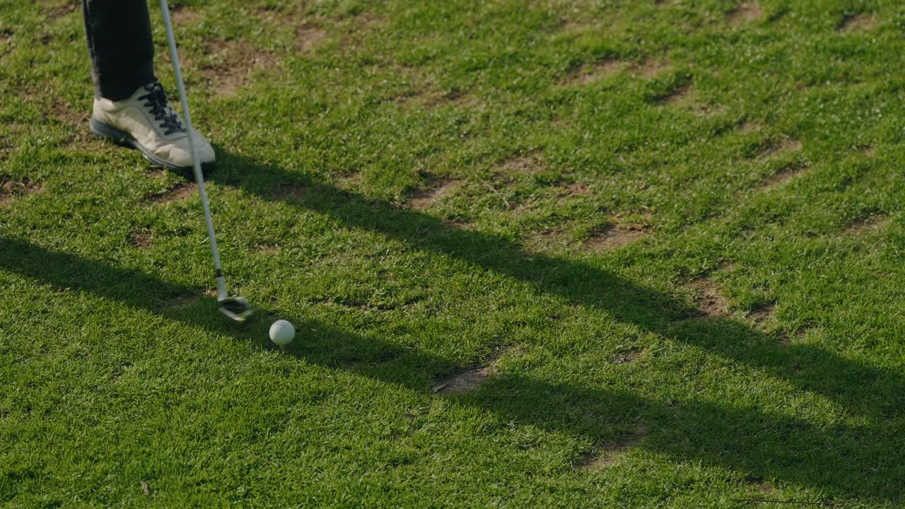 Detailní pohled na golfistu, který udeřil míček holí na greenu