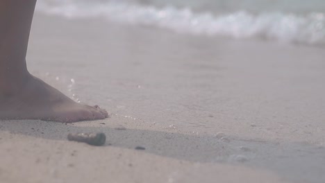 une dame avec une pédicure rouge entre dans de l'eau transparente propre