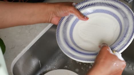 a woman washing dishes in the kitchen sink