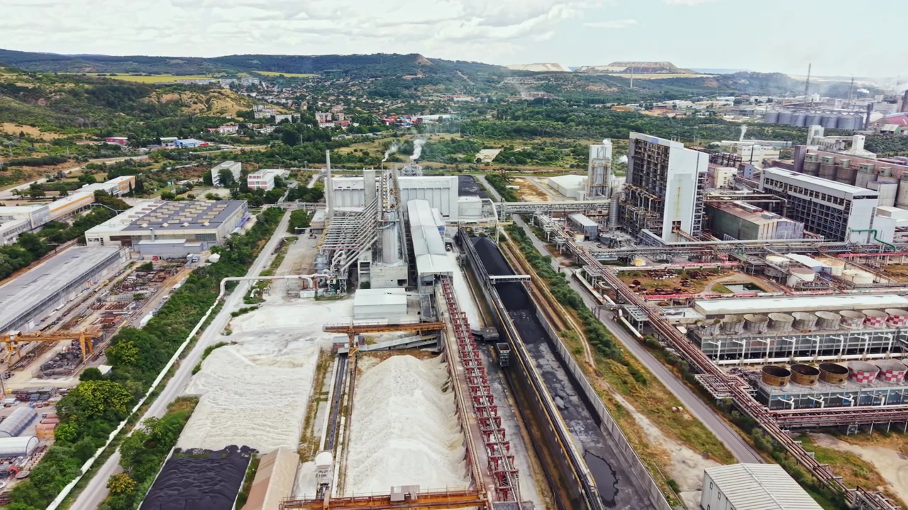 Vista di un'area industriale con fabbriche, magazzini e macchinari vicino a un paesaggio sotto un cielo nuvoloso in una regione europea durante il giorno