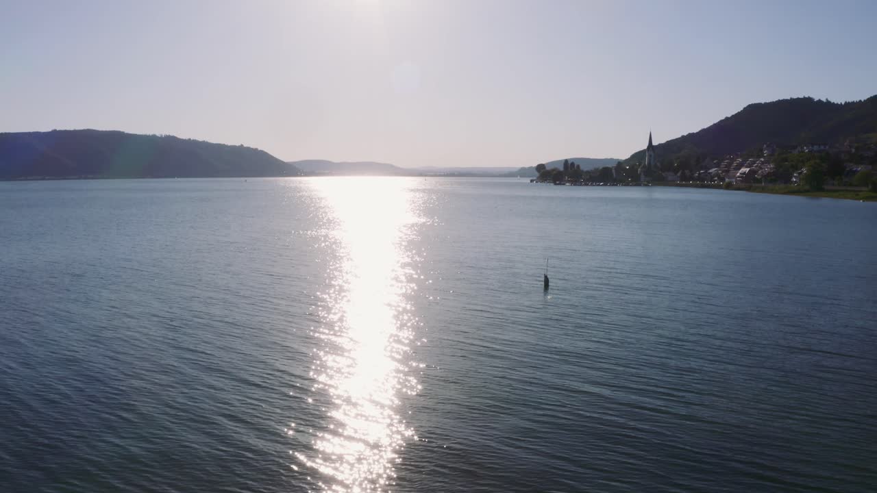 volando sobre el lago con un dron mientras se inclina hacia arriba y revela la puesta de sol en el lago konstanz en alemania