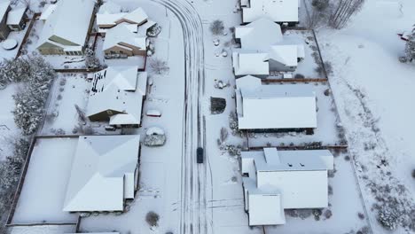 Fotografía-Cenital-De-Un-Coche-Conduciendo-Con-Cautela-Por-Un-Barrio-Nevado