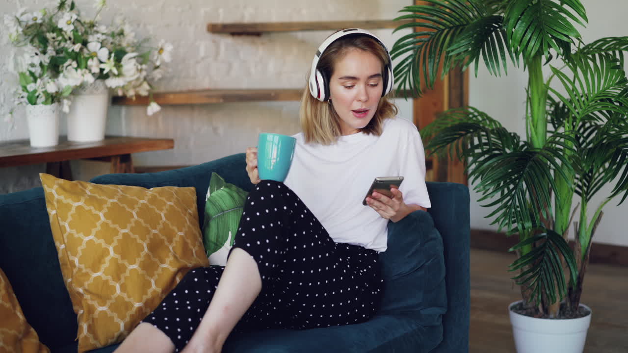 Donna che si rilassa sul divano con le cuffie e il telefono