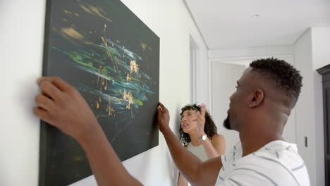 hanging abstract painting on wall, couple decorating home together, enjoying art
