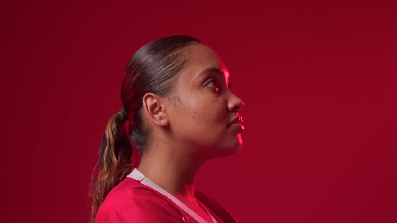 Donna adulta afroamericana che si gira di profilo verso il frontale su indicazione in studio per un ritratto, in maglia rossa