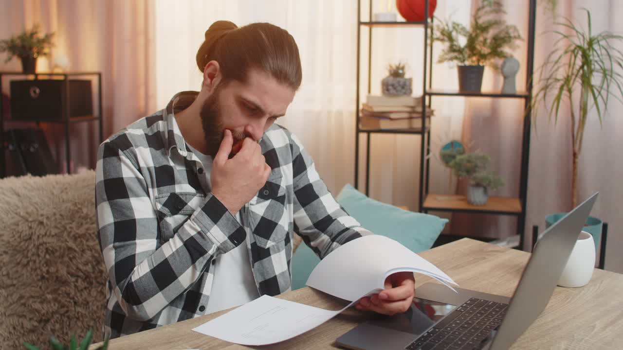 un hombre serio analiza el contrato con un banco en casa. la mesa se agarra a la cabeza con cláusulas de condiciones complejas.