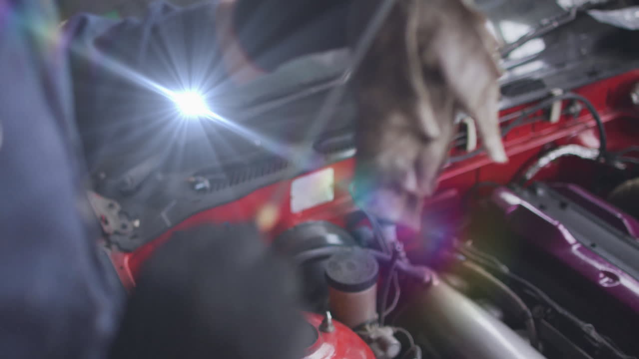 female mechanic wiping engine bay in automotive garage under beam, adding lens flare graphics