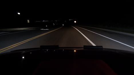 a hood of a car point of view driving at night a car pulling over to the side of the road and a slight decline
