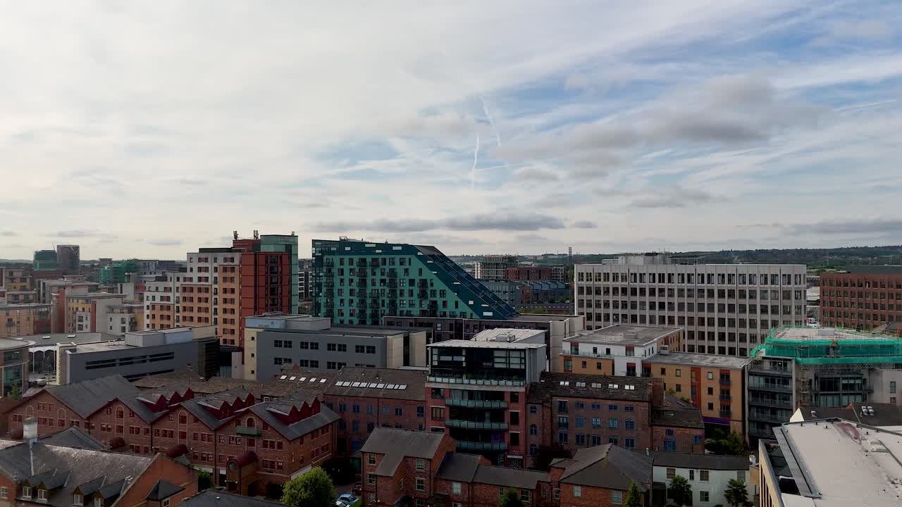 Aerial camera smoothly pans over Leeds city center, revealing Victorian brick buildings, modern architecture, and the River Aire under partly cloudy summer skies
