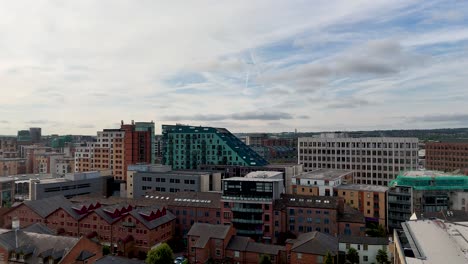 aerial camera smoothly pans over leeds city center, revealing victorian brick buildings, modern architecture, and the river aire under partly cloudy summer skies