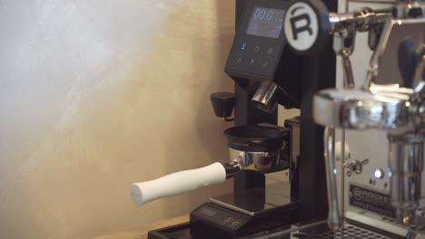 Coffee-shop-employee-put-portafilter-under-electronic-bean-grinder-machine