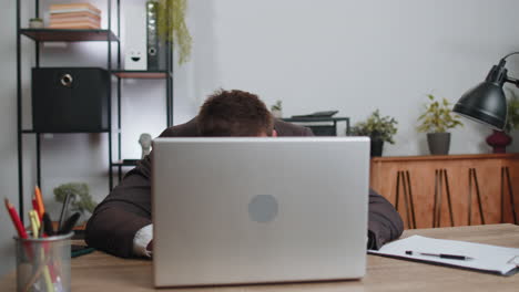 businessman hiding behind laptop computer, making funny face, fooling around, putting his tongue out