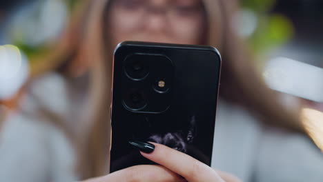 close-up of hand engaging with smartphone, with slightly blurred face in background and soft vibrant bokeh lights, focus on modern technology interaction in digital communication setting