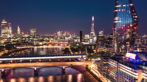 Aerial-night-hyperlapse-footage-of-city.-Forwards-fly-above-Thames-river-at-Blackfriars-Bridge.-Scene-illuminated-by-city-lights.-London,-UK