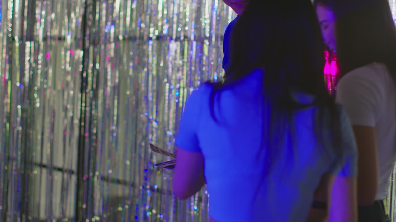 나이트클럽 또는 파인페어 1에서 사진 부스에서 인쇄물을 재미있게 보는 친구 그룹