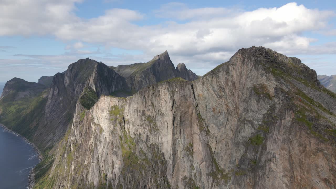 Tilt up aereo di una vasta catena montuosa sull'isola di Senja con la costa in Norvegia durante una giornata nuvolosa
