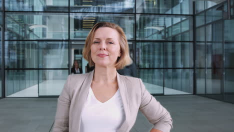 Time-Lapse-Portrait-Of-Mature-Businesswoman-Standing-In-Lobby-Of-Busy-Modern-Office