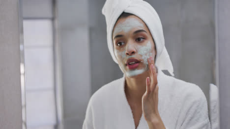 mujer de raza mixta aplicando máscara facial en el baño