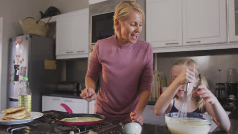 side view of caucasian woman cooking with her daughter at home