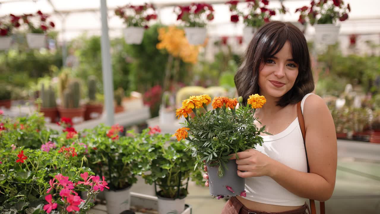 Woman smiling with marigold flowers in vibrant greenhouse