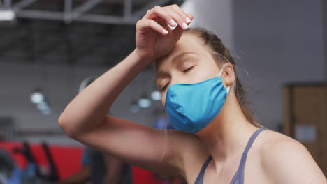 caucasian woman wearing face mask exercising at gym