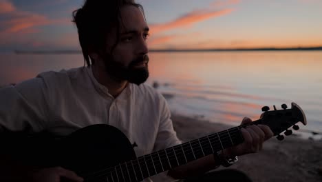 man playing guitar at sunset on the beach