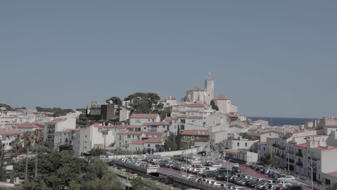 Driving through hundreds of housings with the predominant color of white. wide shot. Look up at settlements against blue sky in Costa Brava, Cadaques, Spain