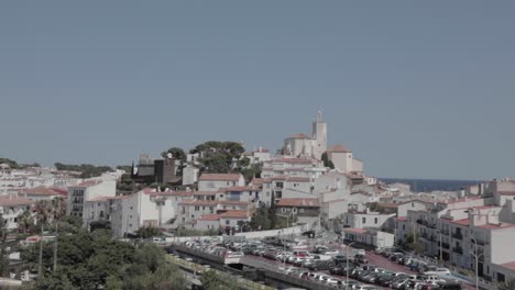 driving through hundreds of housings with the predominant color of white. wide shot. look up at settlements against blue sky in costa brava, cadaques, spain