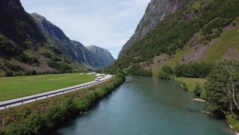 carretera europea e39 que pasa a través de un valle profundo entre el río glacial y campos de pasto verde - antena avanzando lentamente sobre el río