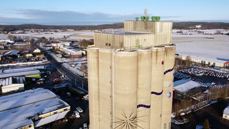 large scandinavian water tower with snaking blue line art work on side on winter day