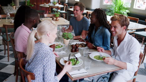 group of young friends enjoying meal in restaurant together