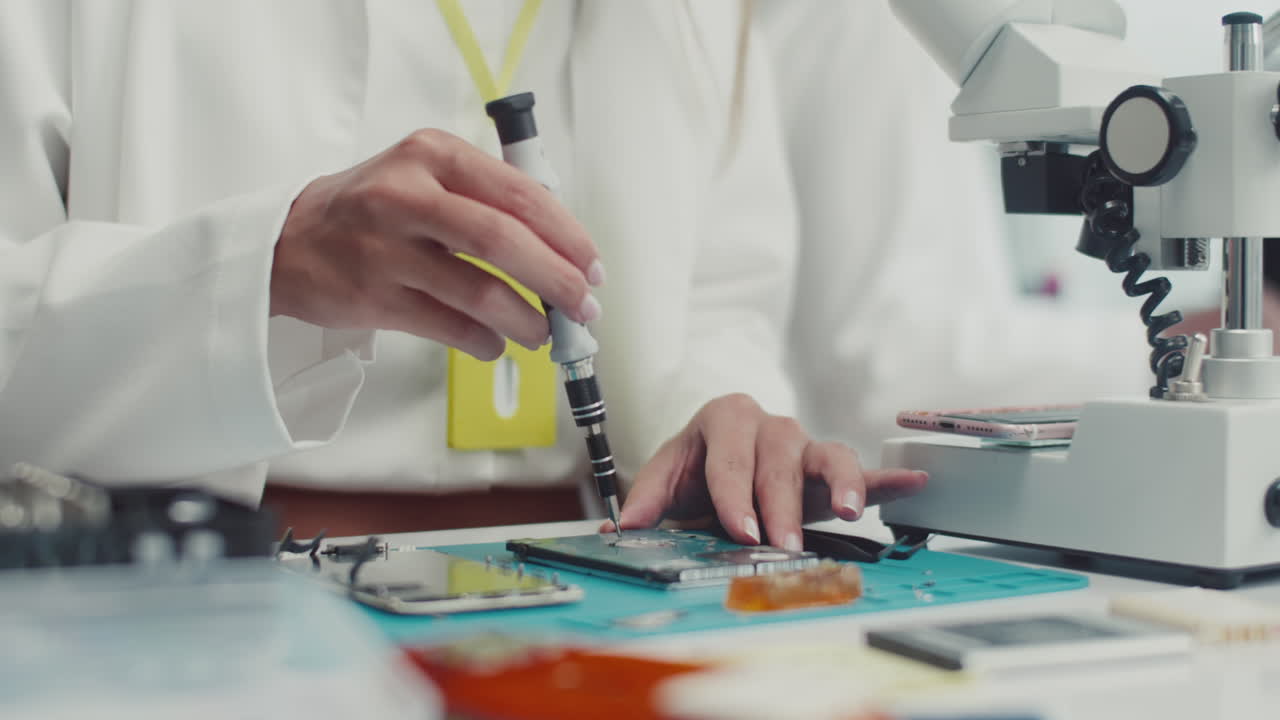 Portrait of Female Technician Unscrewing Component of Broken Device