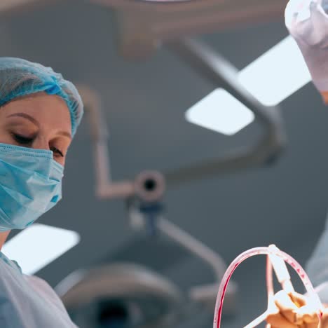 surgeon and a nurse perform a surgery. professional doctor together with female assistant in medical uniform and mask during operation in clinic.