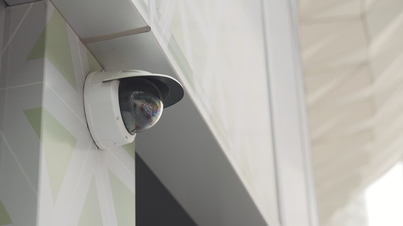 Low-angle static shot of white surveillance camera with hood