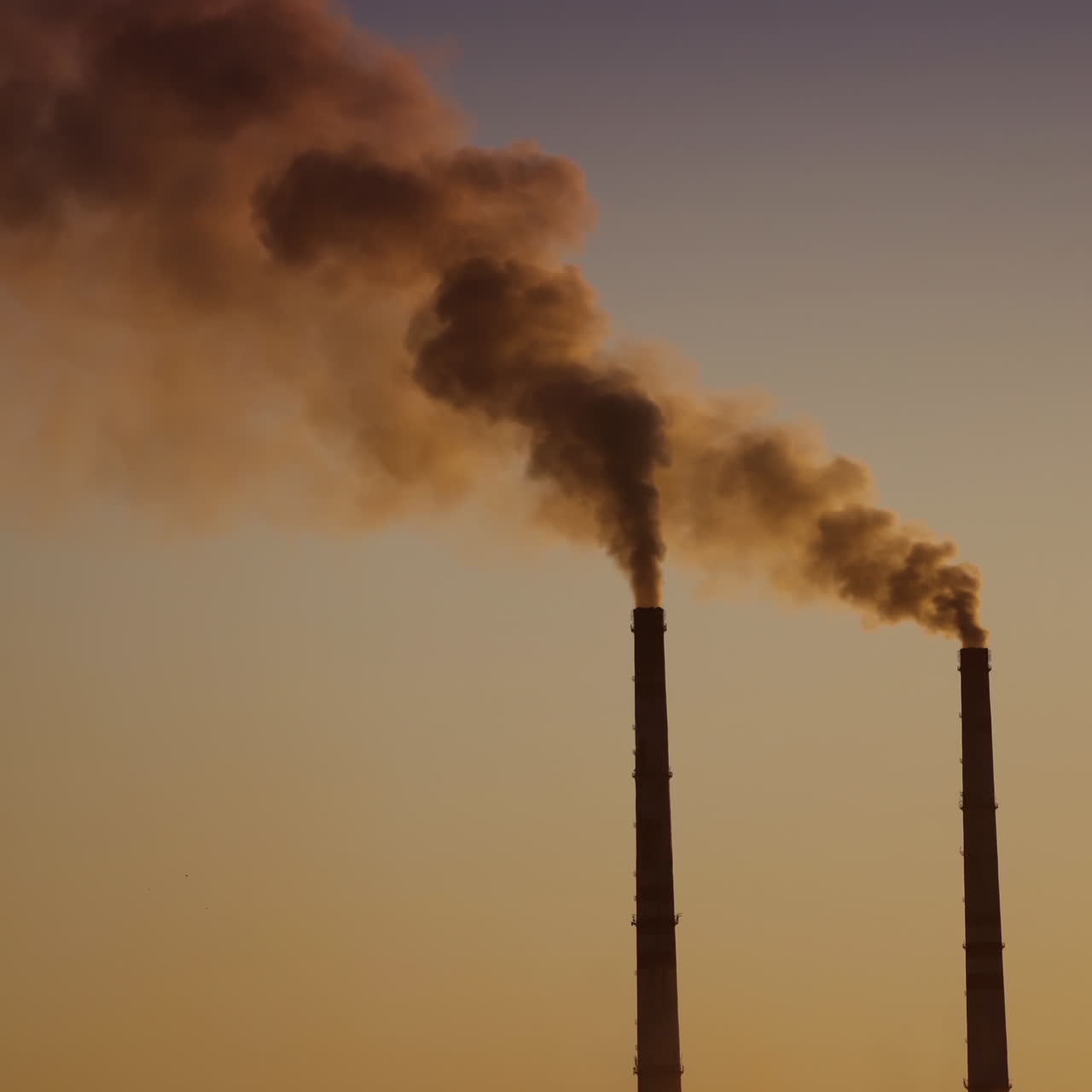 Air pollution by smoke coming out of two factory chimneys. Aerial view.