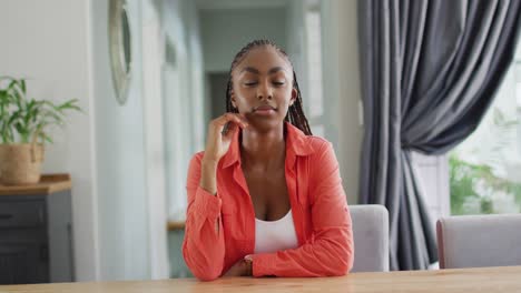 Happy-african-american-woman-sitting-at-table-and-smiling-camera