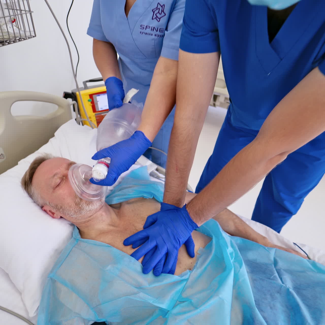 Doctor is doing heart massage to unconscious patient. Male surgeon and a nurse resuscitating man with a defibrillator at the hospital. Top view.