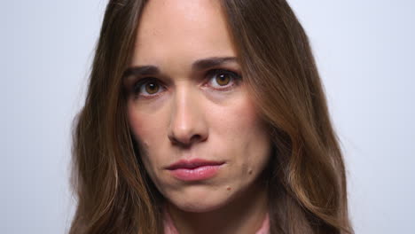 retrato de una mujer triste posando sobre un fondo azul. rostro de mujer descontento