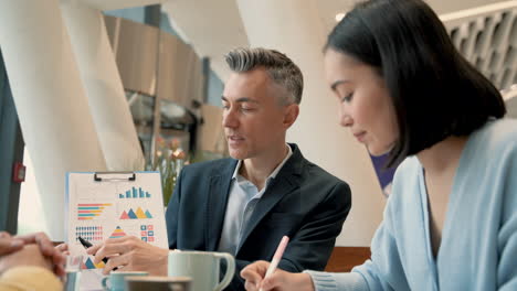 a work team discusses details of some data in a report at a coffee shop