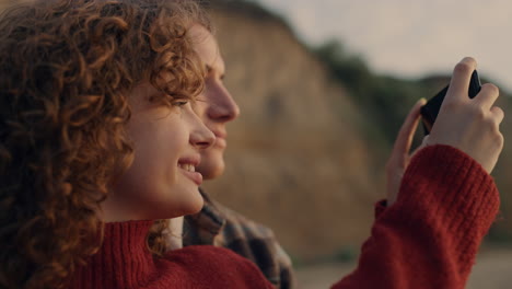 happy couple taking photo on smartphone. joyful girl and guy standing on beach